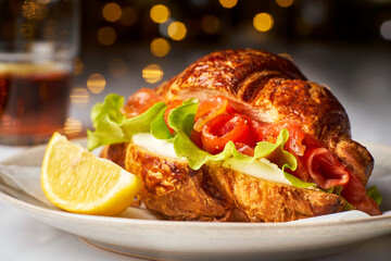 Yummy croissant with salmon and cream cheese on holidays lightings background