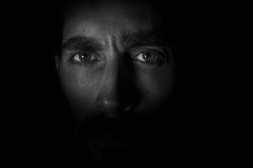 rostro en primer plano de frente a la cámara. en blanco y negro con fondo negro oscuro  