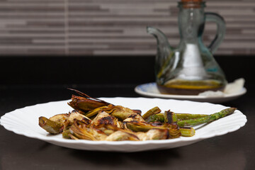 Grilled artichokes and asparagus on a plate and olive oil