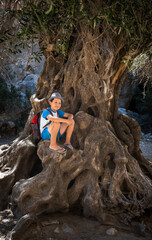 Boy sitting on tree trunk