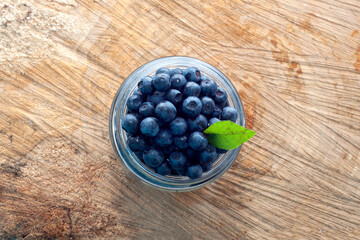 Top view of freshripe blueberries in glass jars on a rustic wood table