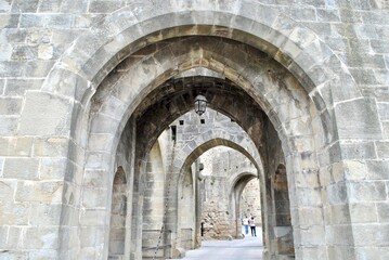 Fototapeta na wymiar A series of arched, stone passageways in Carcassonne, a French fortified city in the region of Occitanie. The citadel, known as the Cité de Carcassonne, is a medieval fortress and UNESCO site.