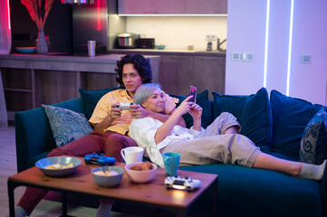 Happy young couple playing a video game sitting at home on a sofa during self isolation on quarantine. - 400622499