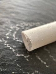 Close up of piece of white chalk on black slate. Blackboard chalk manufacturers now may use mineral...