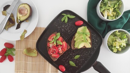 Tomatoes and Avocados toasted bread in a black grill pan