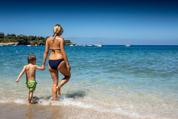 Fototapeta na wymiar Mother and son walking into sea