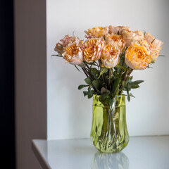 bouquet of orange roses in a vase of old green glass on the windowsill.