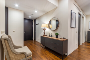 Entrance hall in the bright luxury apartment. Hallway dresser with lamp