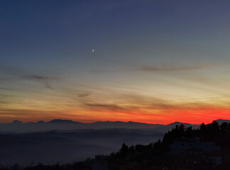 Tramonto sulle montagne, colline e valli dell'Appennino con la luna nel cielo