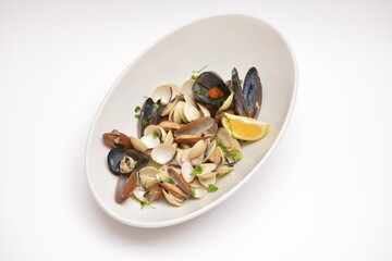 Seafood on a white oval plate. Decorated with lemon wedges. Located on a white background. Can be used in the restaurant menu.