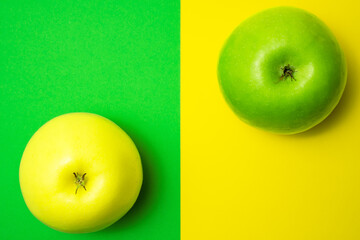 One green apple on yellow background and one yellow apple on green background.  Difference or opposition concept.