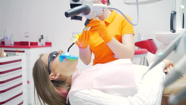 Dental curing light used for teeth treatment, modern equipment, process closeup. Dentist doing procedure with UV light in clinic. equipment that is used for polymerization resin based composites