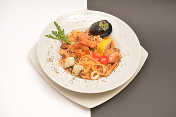 Pasta with seafood on a white plate. Located on a black and white background. Can be used in the restaurant menu.