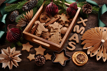 Christmas flat lay with gingerbread cookies in wooden tray and paper decors