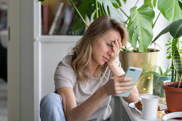 Confused caucasian woman doing facepalm gesture, touching head with palm, looking at screen mobile...