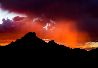 Arizona Monsoon Sunset with Purple and Orange Rain and Black Mountain Silhouette