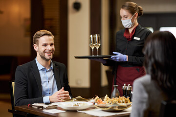 Two young people on date being served by a mindful waitress