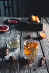 Citrus tea in a transparent glass, healthy drink on a wooden background.