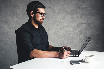 A man sits with a laptop in a black shirt. Business concept, work. Office routine. Property efforts