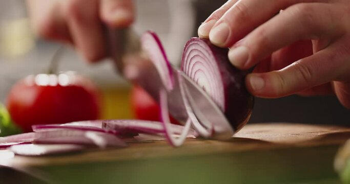 Chef using a knife cutting fresh raw onions. Cooker at home making a healthy vegetable meal, cutting up veggies - food and drink 4k footage