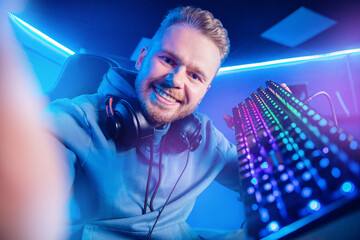 Professional gamer man smile making selfie photo and playing tournaments online video games computer with headphones © Parilov