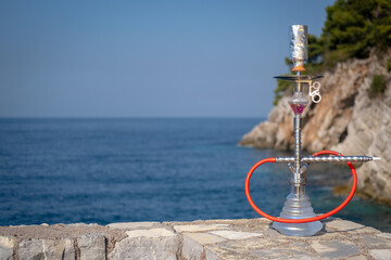 Hookah on the background of the blue sea and rocks.