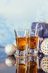 Two glasses of whiskey or bourbon with Christmas decoration on a light bokeh background. New Year, Christmas and winter holidays whiskey mood concept