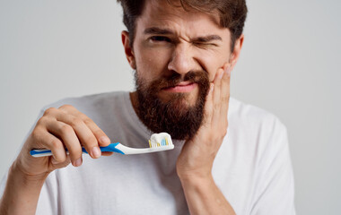 a man with a toothbrush gestures with his hands pain in the oral cavity morning procedures