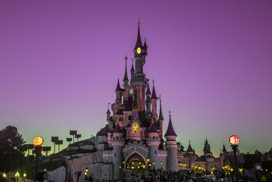 Castle of Sleeping Beauty in Dineyland Paris with lights on and a cloudless night sky