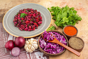 top view vegetable salad on a ceramic plate made of red onions garlic parsley bunch and black pepper ground pepper turmeric and chopped red cabbage on a wooden background