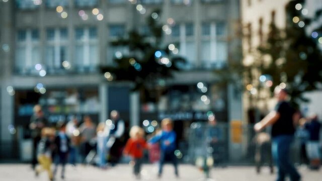 Urban landscape before COVID pandemic worldwide - defocused background with people pedestrian silhouettes and lots of soap bubbles in the air on a warm summer day - beautiful bokeh
