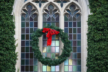 Pine wreath with red ribbon on exterior of gothic stone framed leaded glass church window