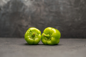 Front close view of two fresh green peppers on dark background