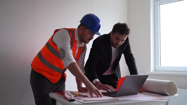Male contactor and entrepreneur using laptop..Businessman and male architect browsing drafts on laptop while working on project in workplace together