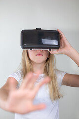 Portrait of little girl in a white t-shirt  using virtual reality headset on white background