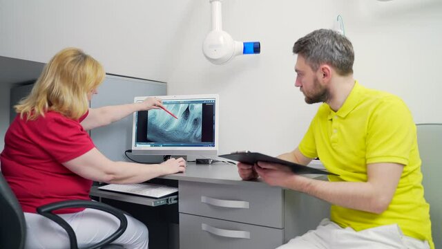 Medical dentist team in dental office discuss and examining x-ray image. looking at computer Desktop screen in modern dental clinic x-ray room In Hospital 