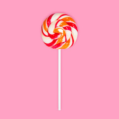 Lollipop on a pink background. Red and white candy.