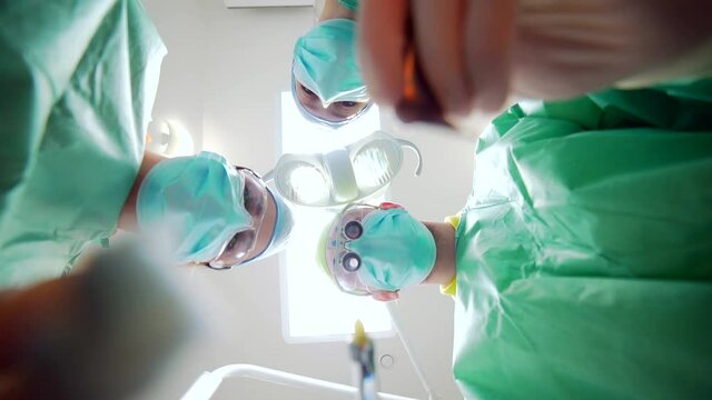 Team of Doctors and Nurses over Patient Point of View. operation view from below. Patient looking to the face of the surgeons in protective masks. group medic working in hospital operating room.