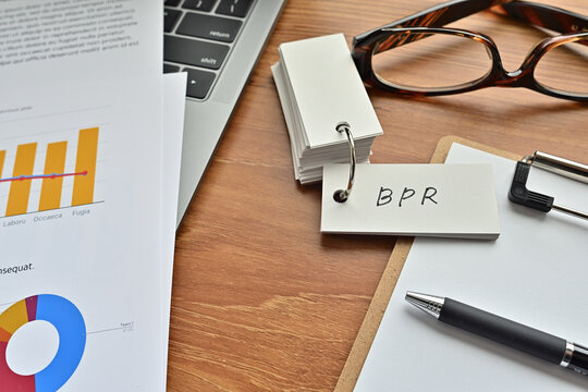 There is a piece of paper with a graph printed on it, a clipboard, and an open vocabulary book on the desk. The word BPR is there. It's an acronym that means Business Process Re-engineering.