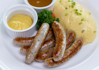 Six Bavarian grilled Nuremberg sausages served with potato mash, dark beer jus and mustard