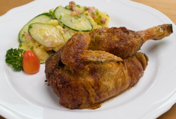 Grilled half chicken served with German potato cucumber salad with bacon
