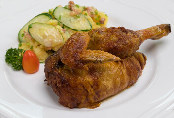 Grilled half chicken served with German potato cucumber salad with bacon
