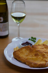Crumbed pork escalope called Schnitzel served with French fries, cranberry sauce and lemon