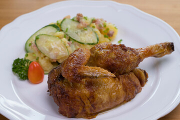 Grilled half chicken served with German potato cucumber salad with bacon