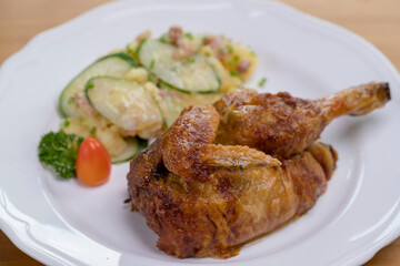 Grilled half chicken served with German potato cucumber salad with bacon