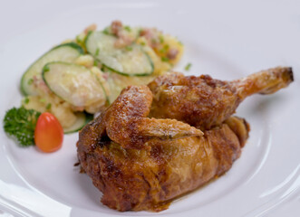 Grilled half chicken served with German potato cucumber salad with bacon