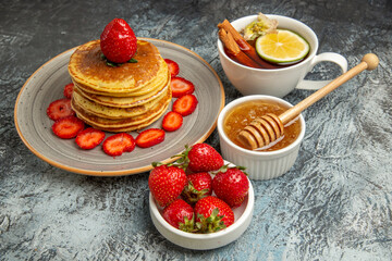 front view yummy pancakes with strawberries and cup of tea on light background cake fruit sweet
