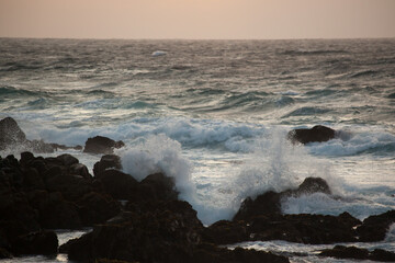 Ocean crashing onto a rocky shore at sunset