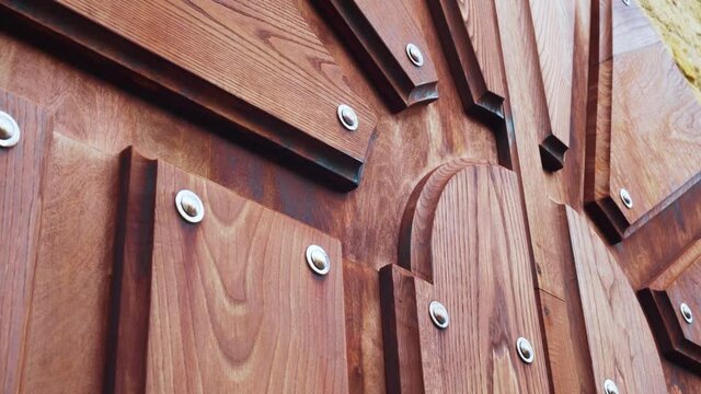 Carved relief gate door made of textured material. Stainless steel metal rivets. Close up