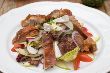 Mix leaves with pork roast slices, crackling, apple, Camembert cheese, cherry tomatoes, and apple vinaigrette